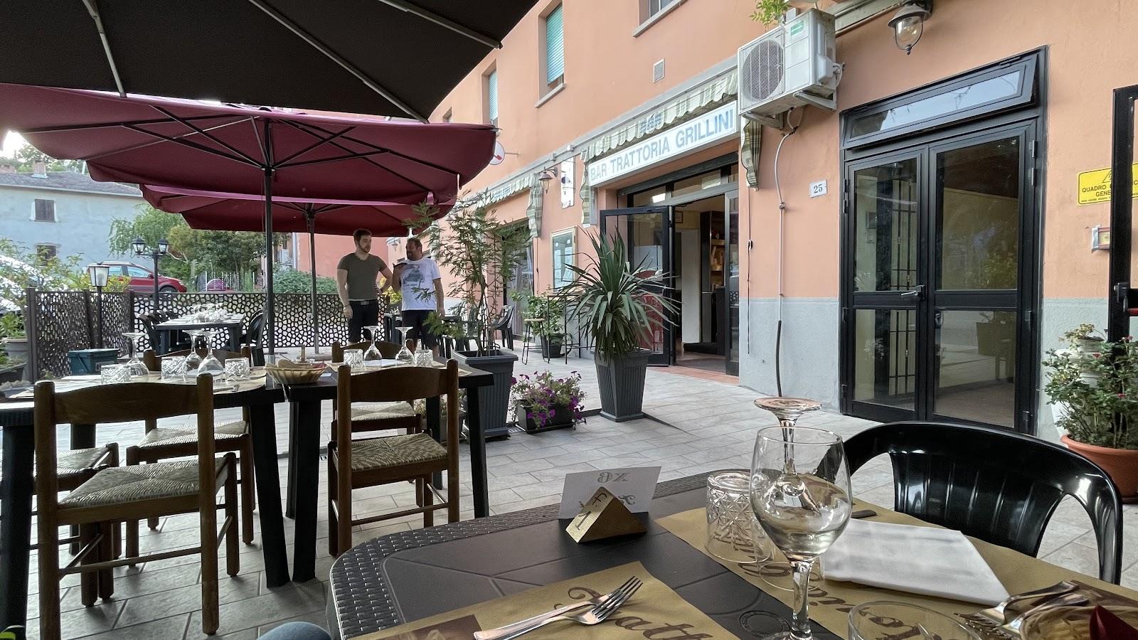 Il dehors della Trattoria Grillini, con gli ombrelloni bordeaux davanti alla facciata color pesca